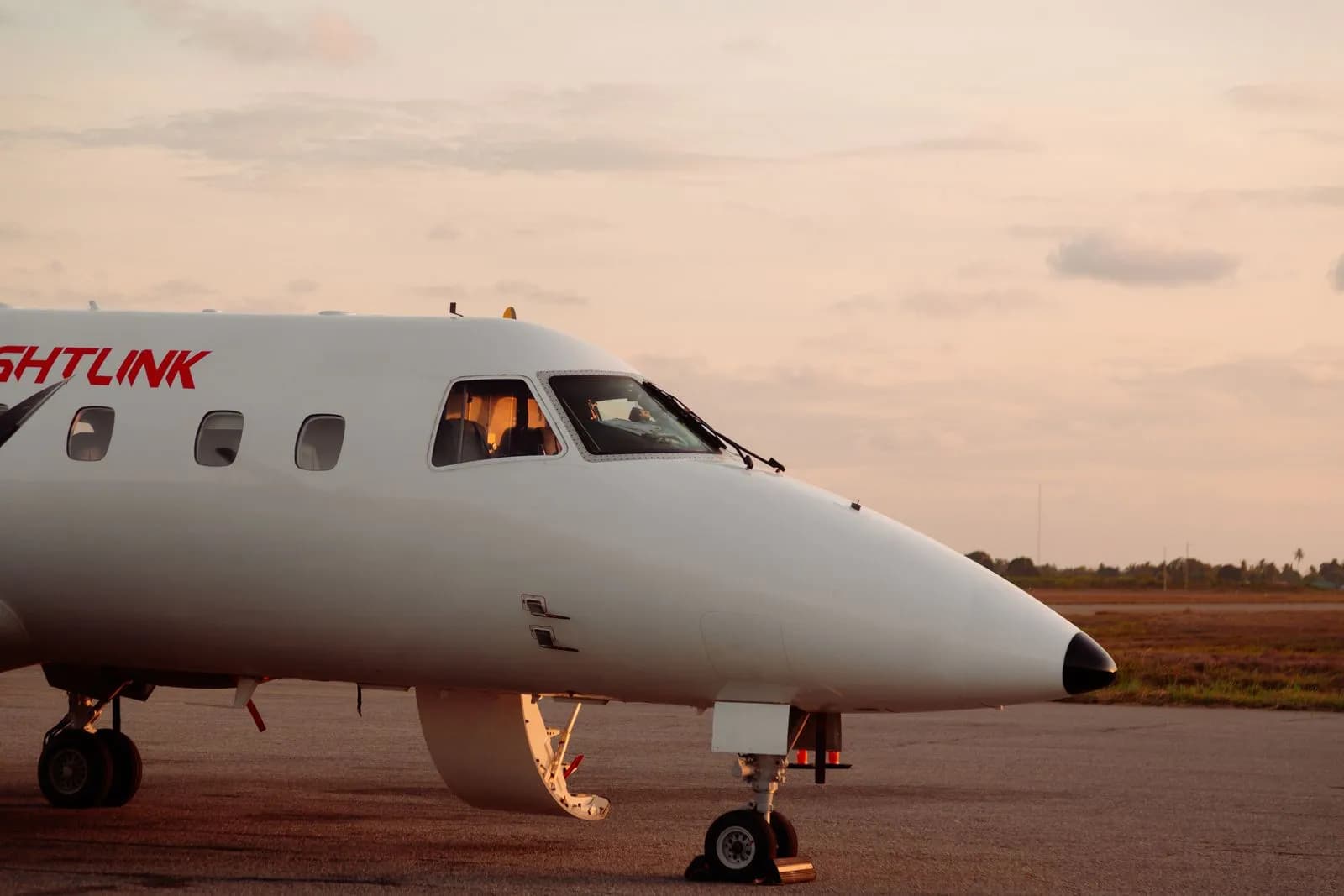 White commercial airplane parked on airport tarmac during sunset for travel and aviation concepts