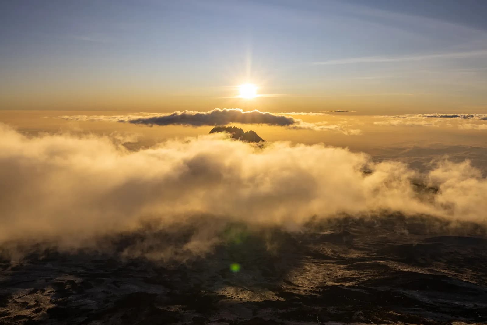 Golden sunrise over mountain peak above thick clouds in a scenic aerial landscape view