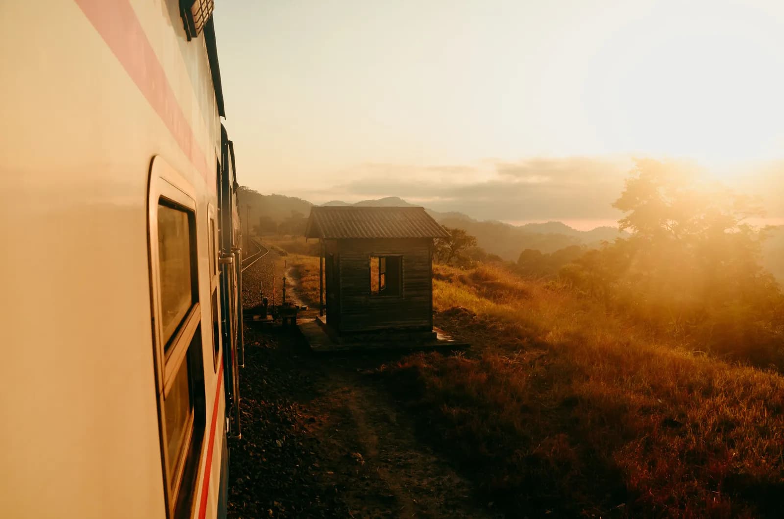 Vintage camper parked near rustic cabin during golden hour mountain landscape
