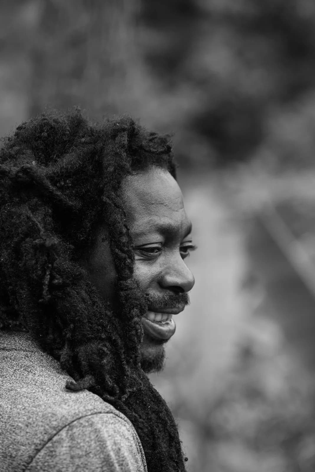 Black and white portrait of a smiling african american man with dreadlocks in nature