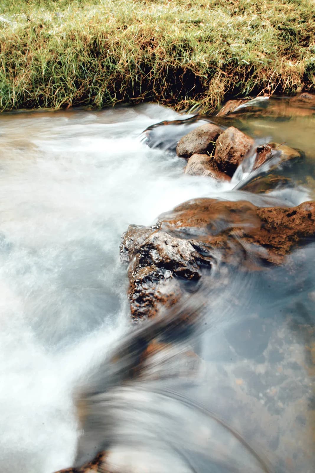 Fast flowing river water cascading over smooth rocks in natural stream