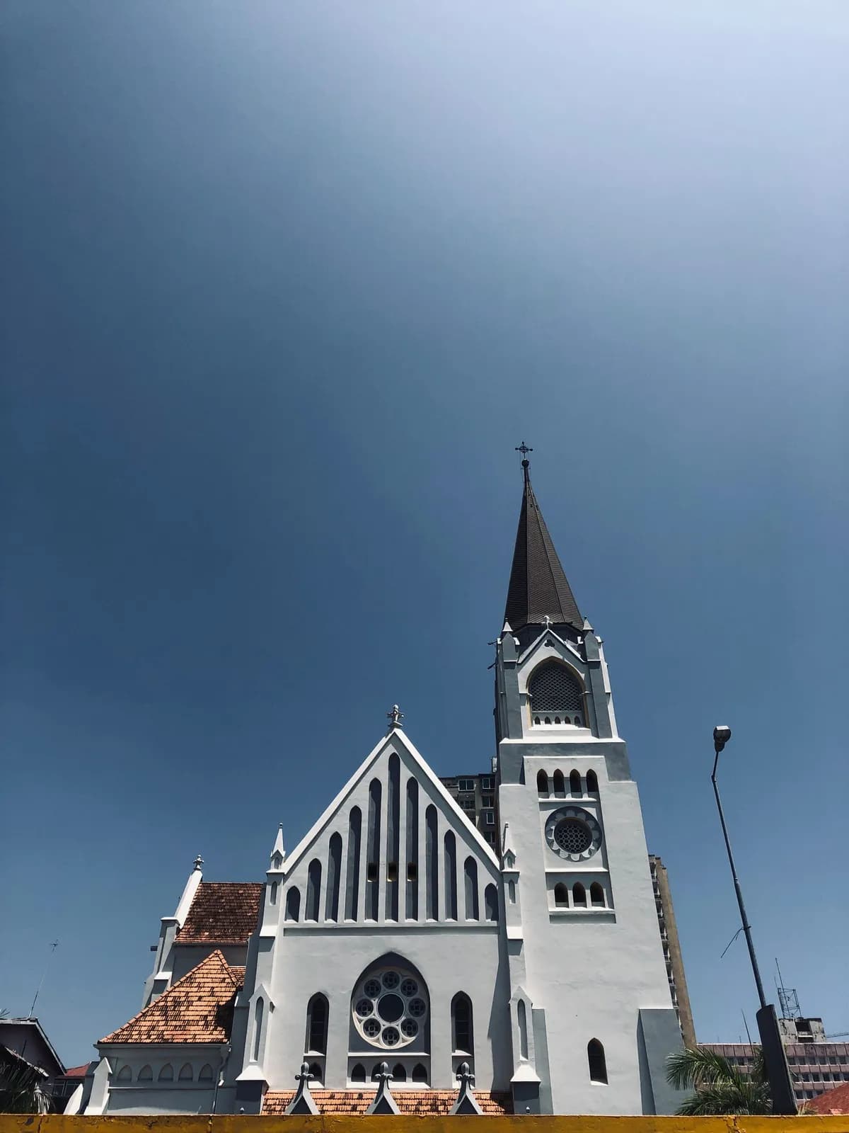 Historic christian church building with tall steeple against a clear blue sky in urban setting