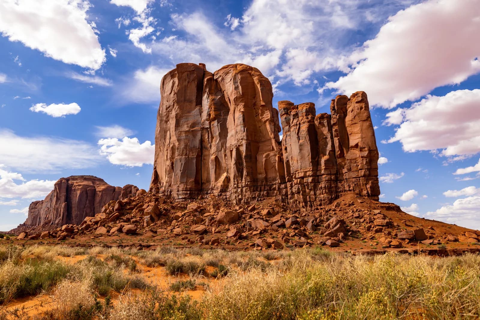 Scenic view of monument valley sandstone buttes under a bright blue sky with fluffy white clouds