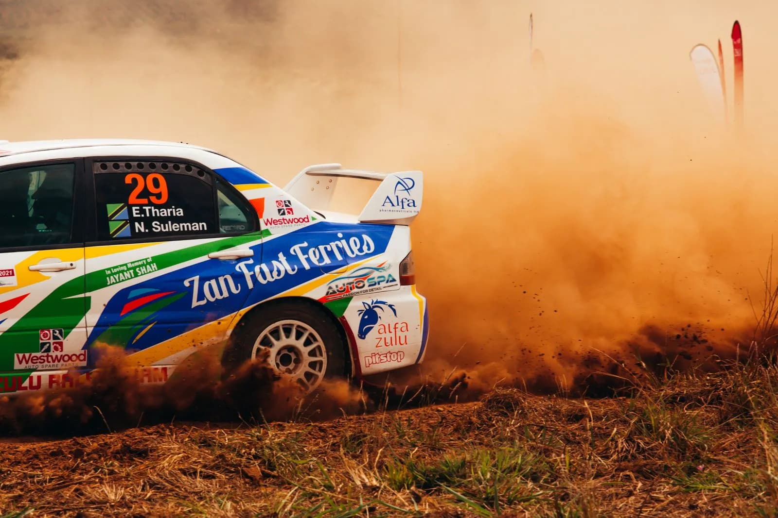 Rally car drifting on dirt track kicking up dust during a professional off road racing competition
