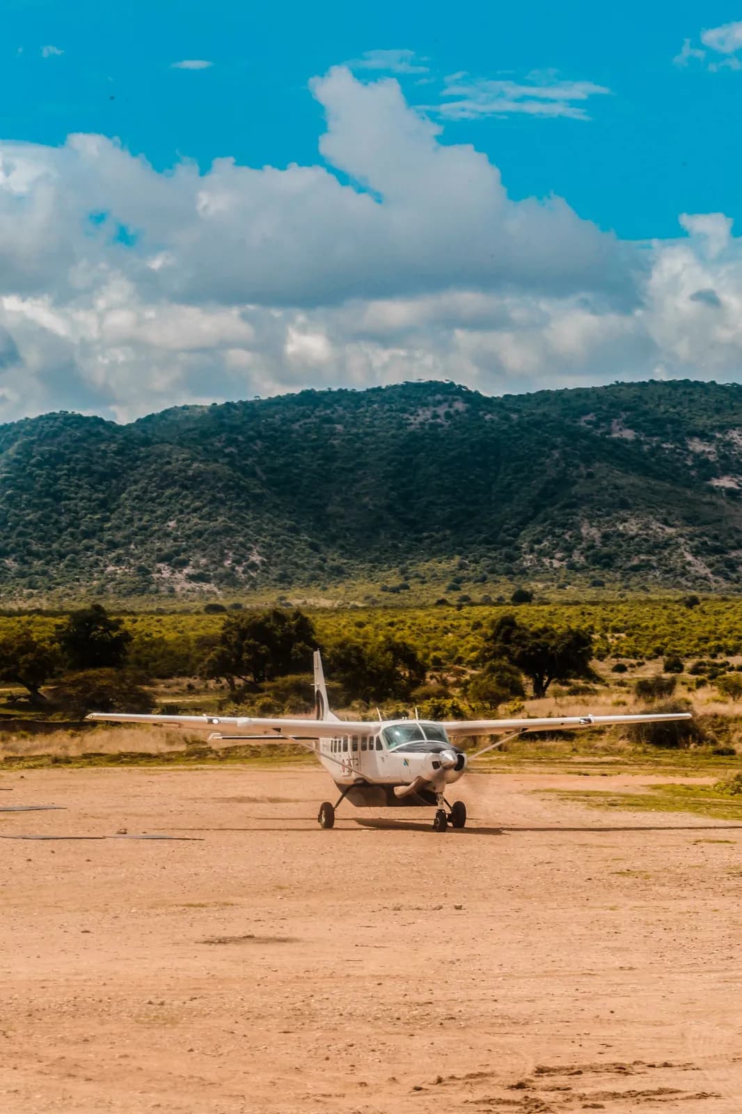 Small bush plane landing on a remote dirt airstrip in the african savanna landscape