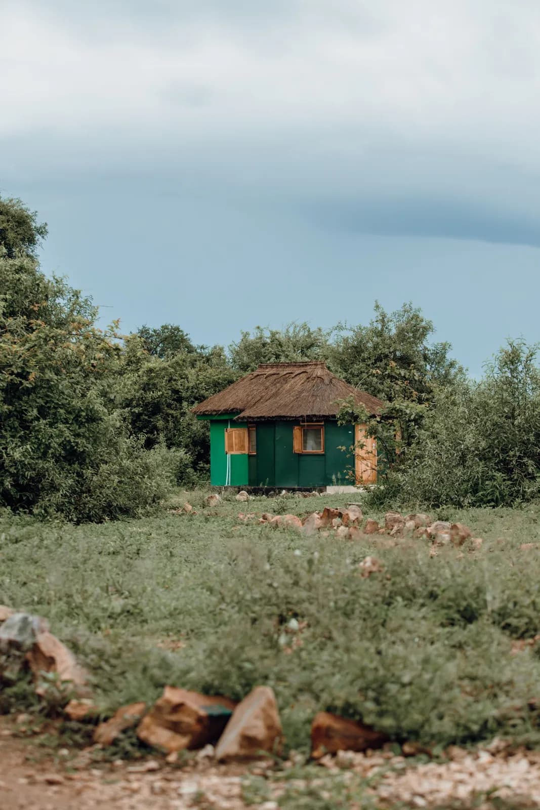 Small green cabin with thatched roof in a rural landscape during a cloudy day for travel concepts