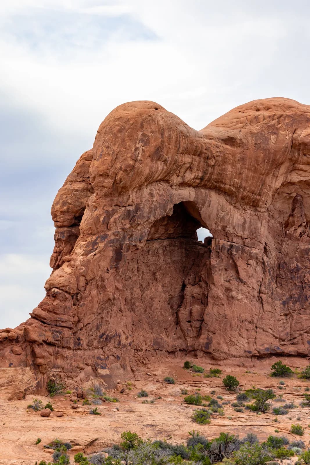 Natural sandstone arch formation in the desert landscape under a cloudy sky in utah