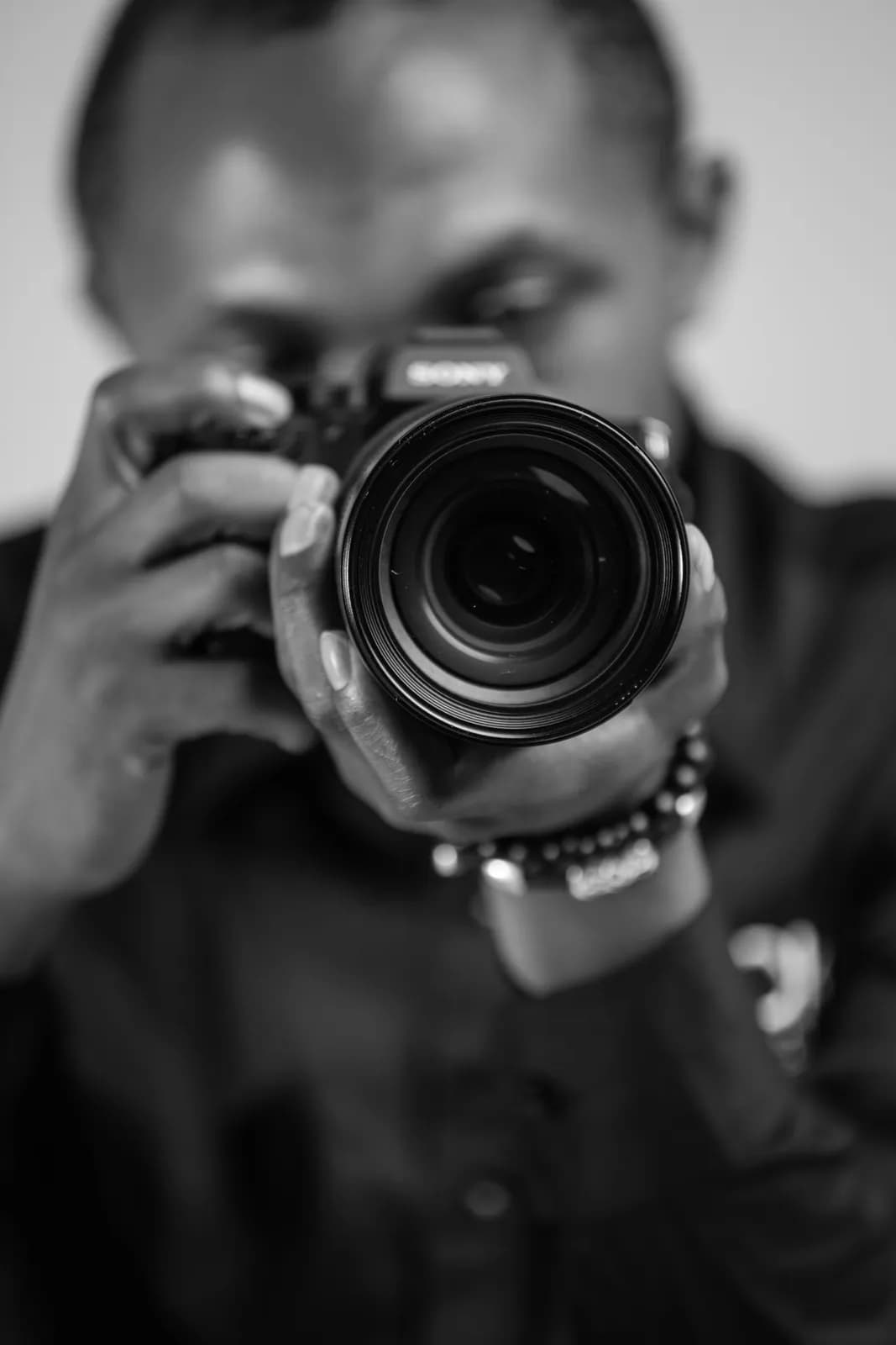 Professional black male photographer holding a camera taking a picture in a studio setting