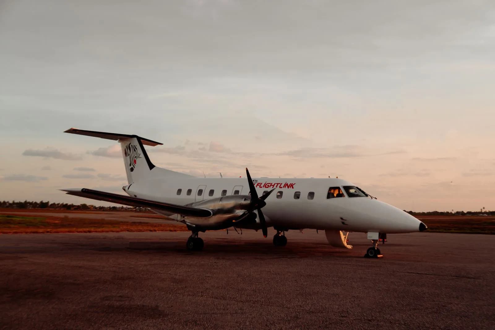 Commercial turboprop airplane parked on the airport tarmac during a golden hour sunset