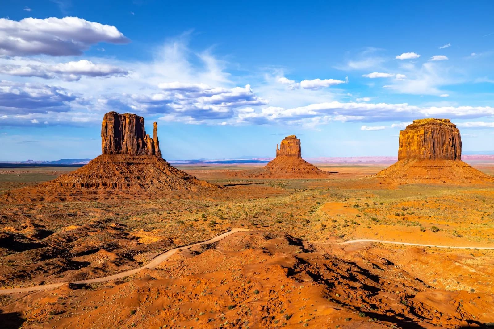 Iconic desert landscape with three towering red rock formations under clear blue sky