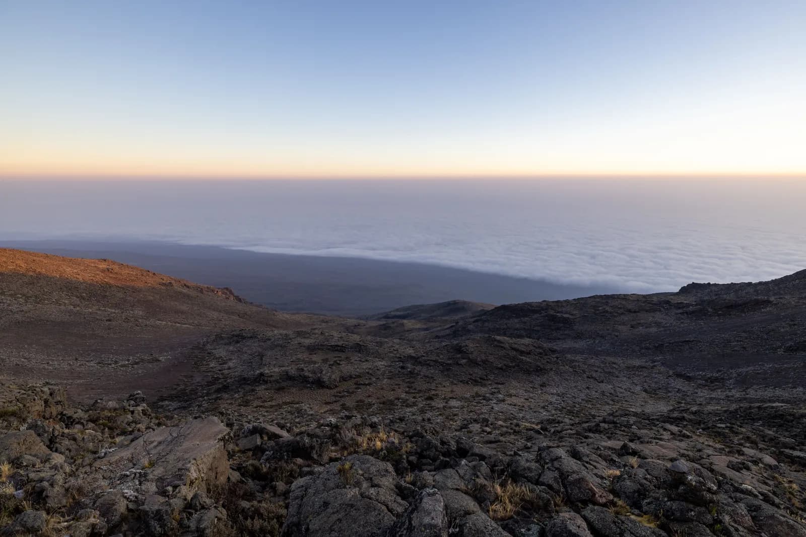 Panoramic view of volcanic landscape above clouds at sunrise from high mountain peak summit