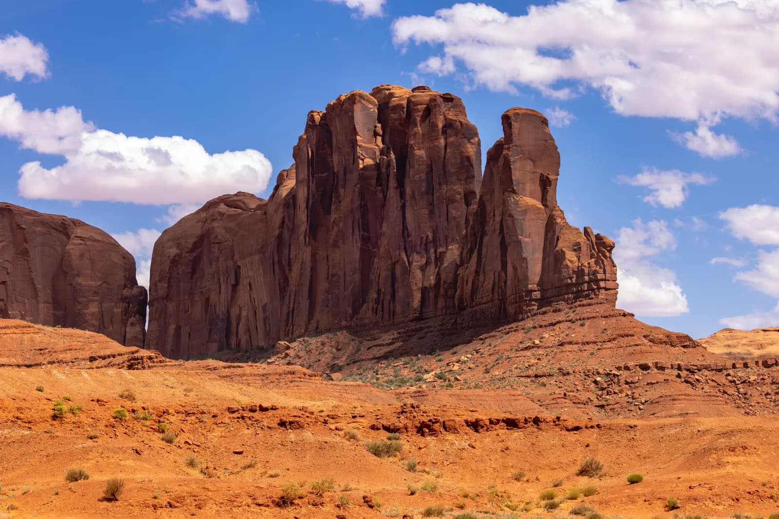 Majestic red sandstone butte in monument valley desert landscape under blue sky with white clouds