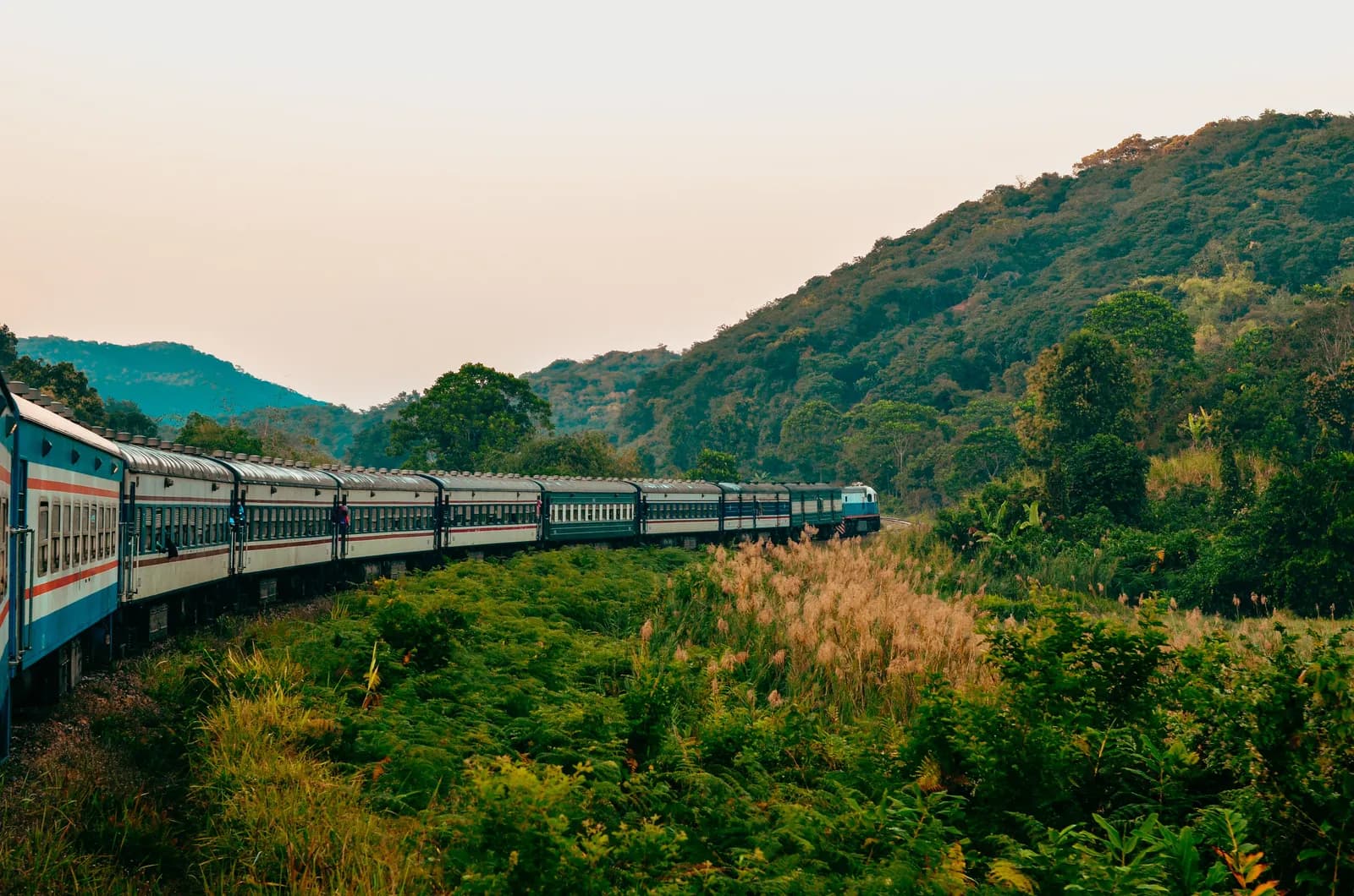 Scenic passenger train traveling through lush green mountainous countryside