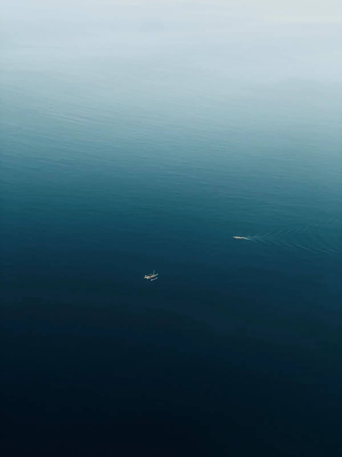 Aerial view of a small fishing boat sailing on the deep blue calm ocean water surface