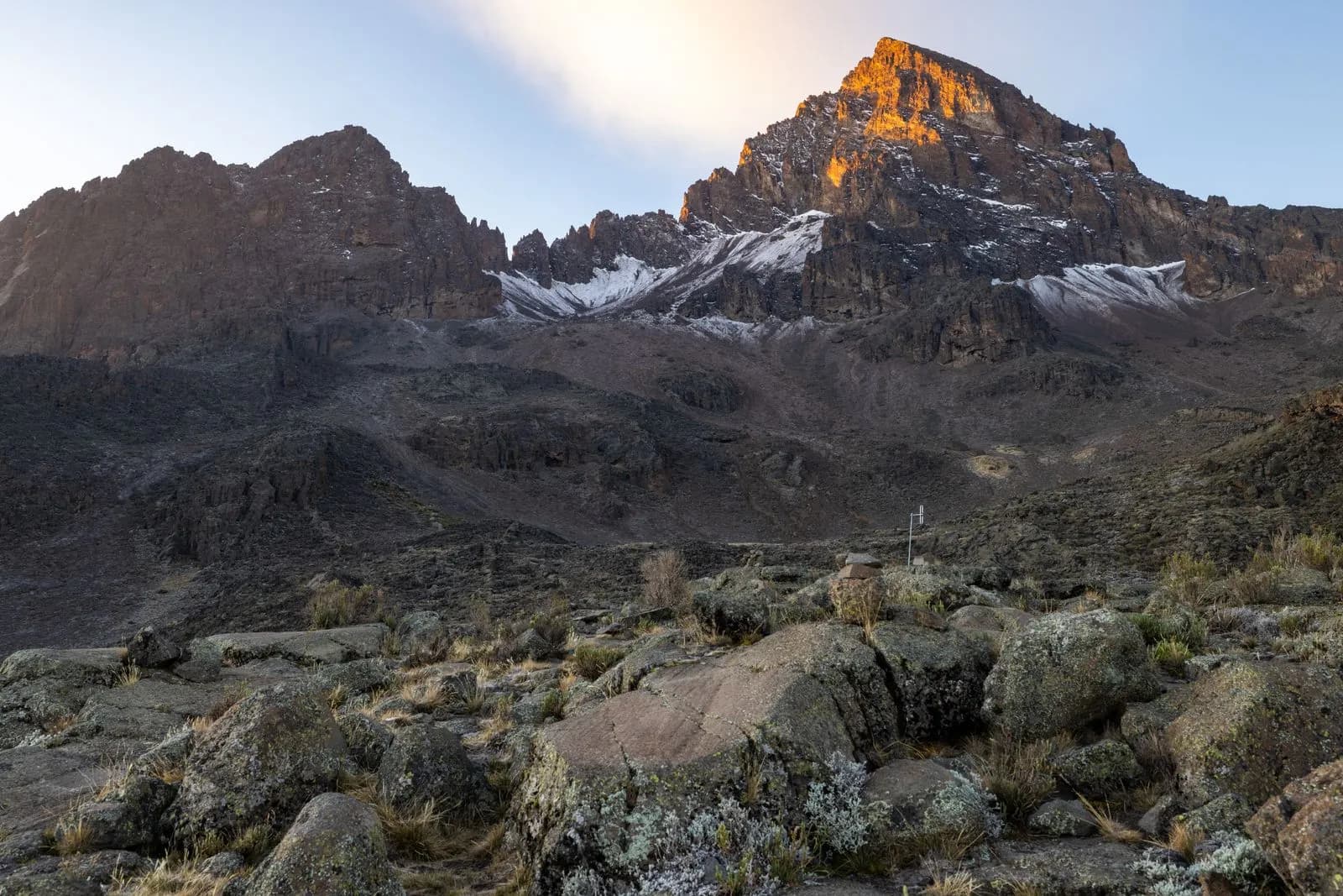 Golden sunrise light on mount kenya peaks with rocky terrain and snow in the early morning light