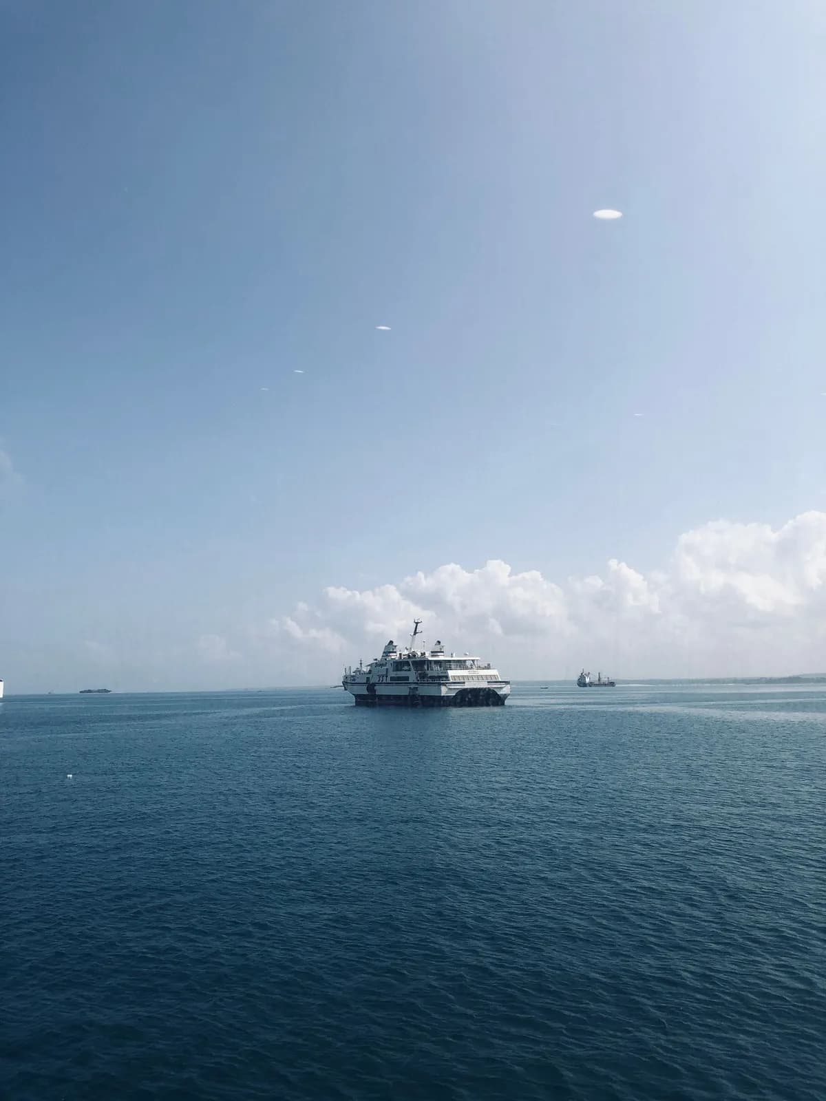 Passenger ferry boat cruising across the calm blue ocean on a sunny day with clear sky