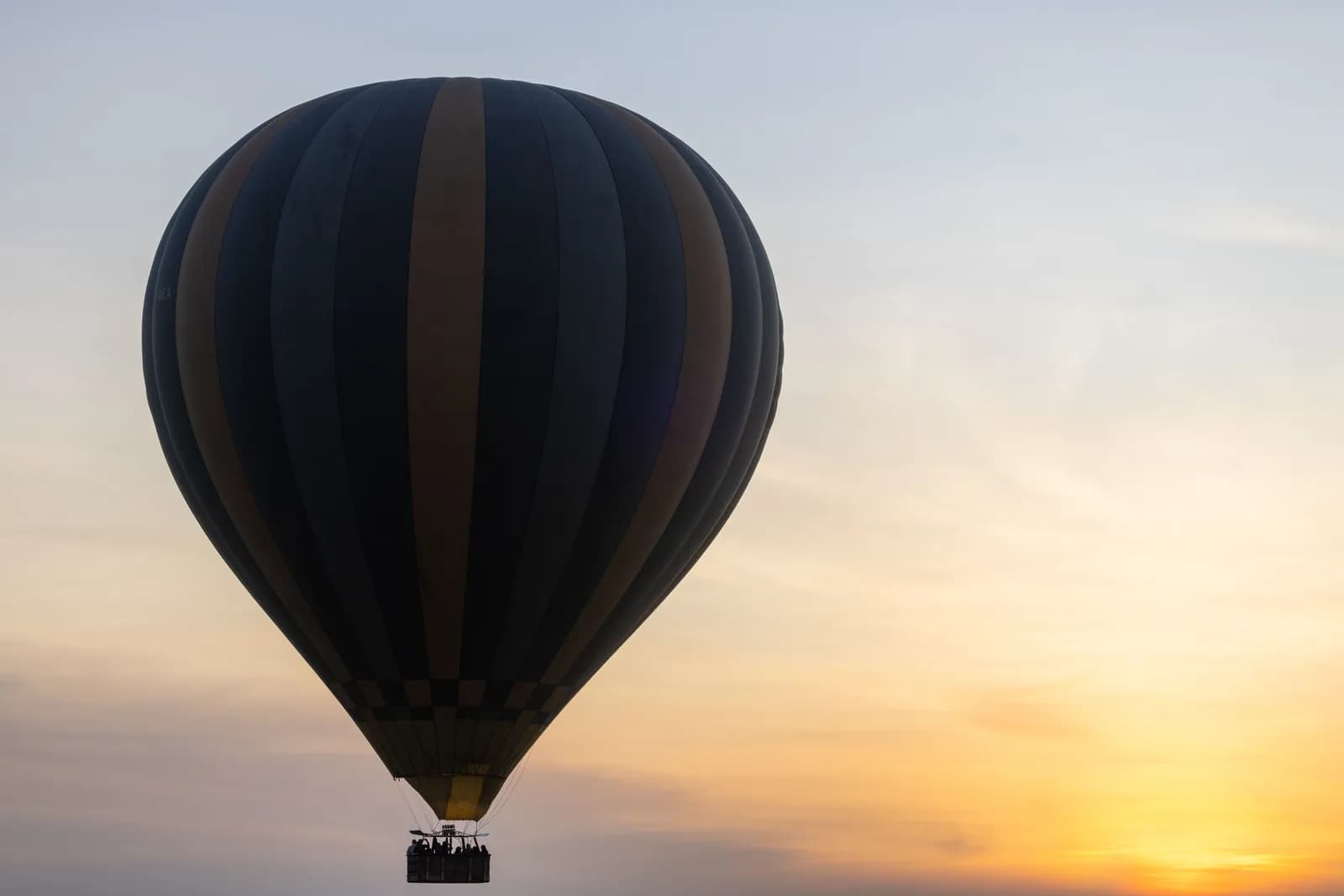 Hot air balloon flying in the sky during a beautiful golden sunrise for travel and adventure concepts