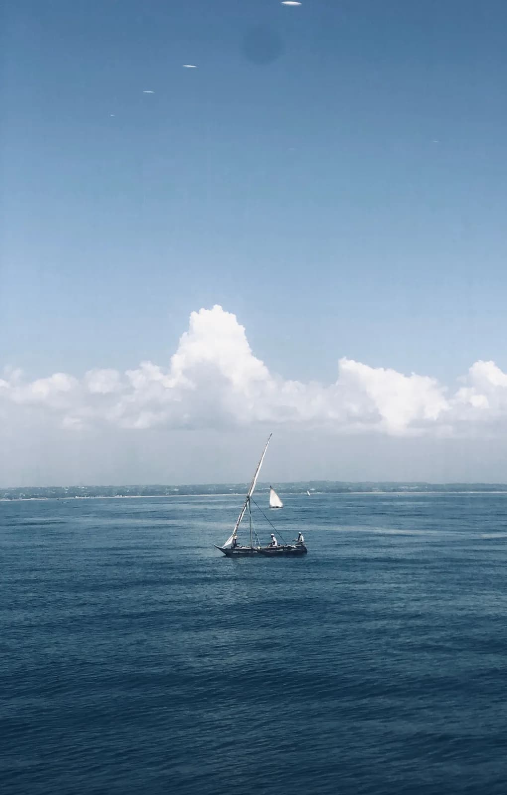 Traditional dhow sailboat navigating across the open ocean under a bright blue summer sky