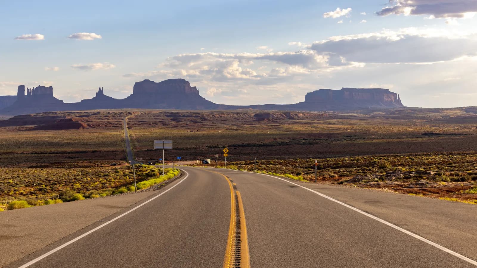 Scenic asphalt road leading through monument valley desert landscape at sunset in arizona usa