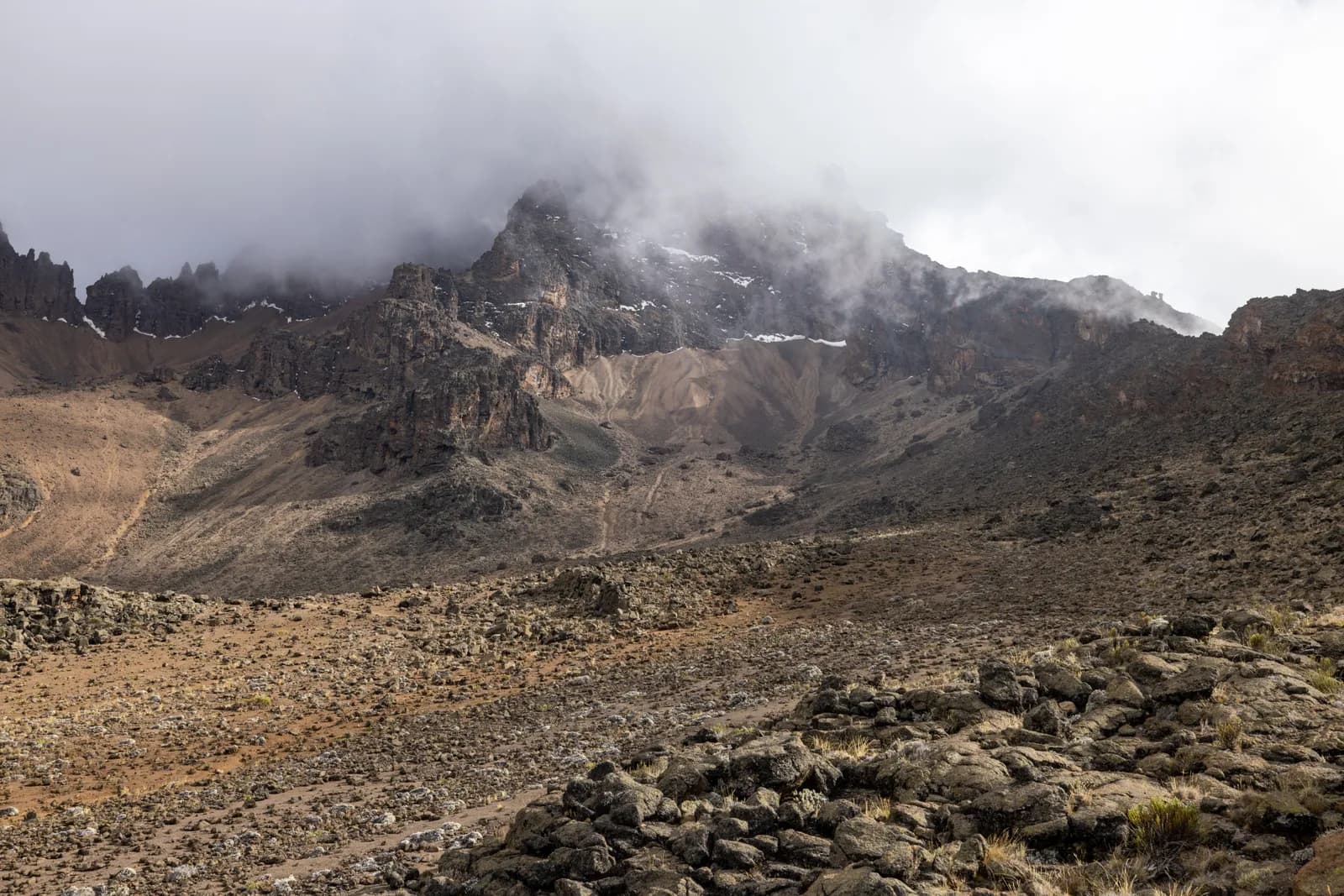 Rugged mountain landscape with rocky terrain and misty clouds covering the high peak summit