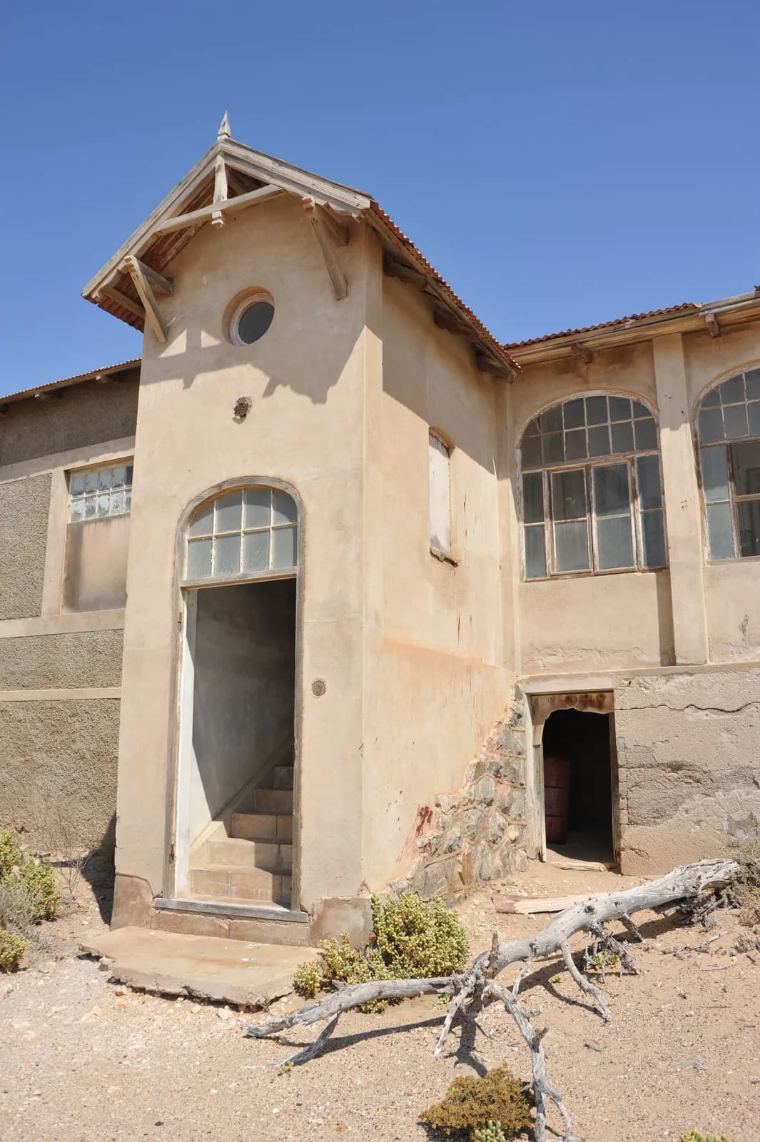 Abandoned historic building exterior with weathered stucco walls and arched windows in desert landscape