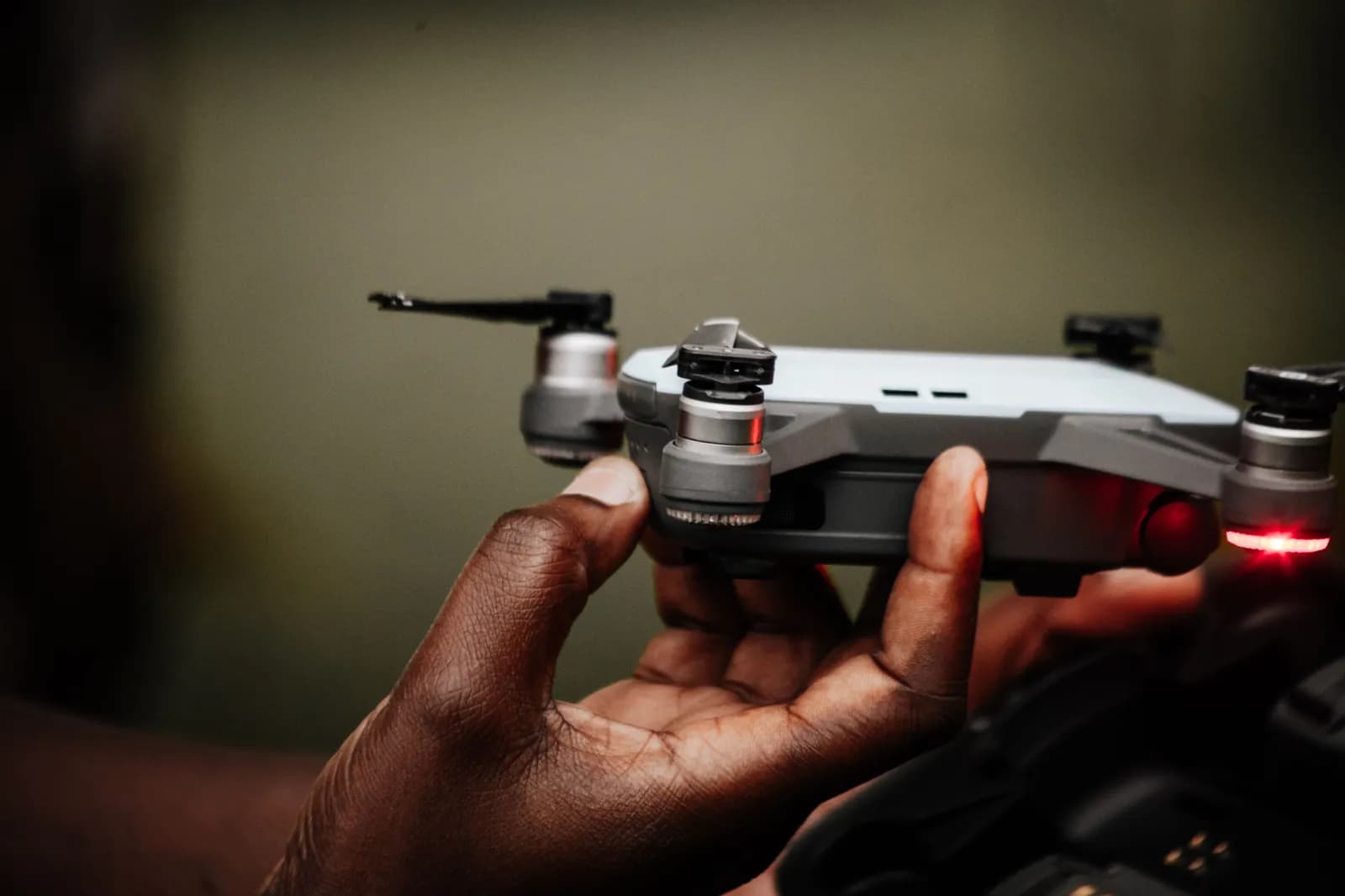 Person holding a small quadcopter drone with glowing red lights for aerial photography and filming