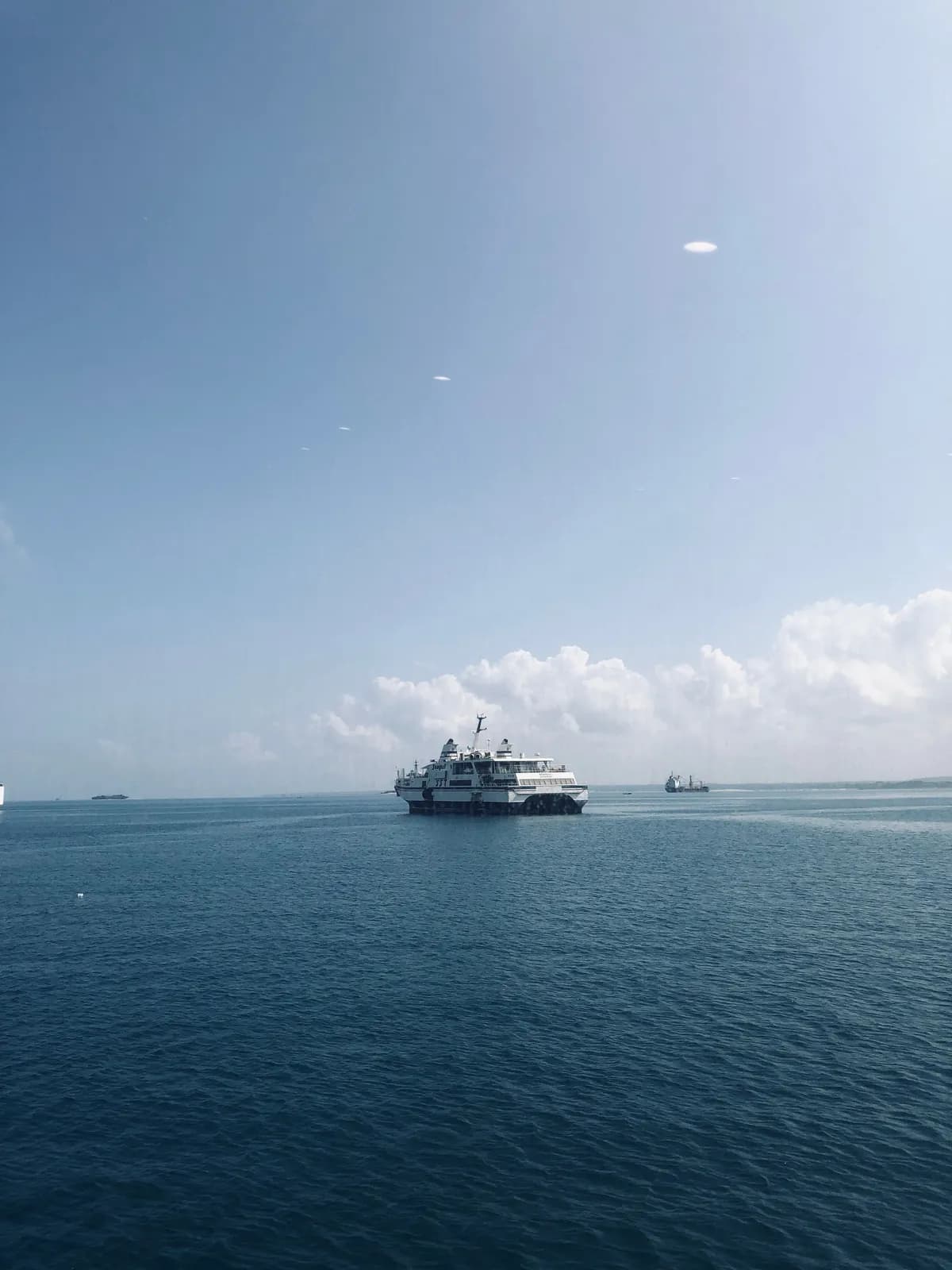 Passenger ferry boat sailing across the blue ocean water on a sunny day with clear sky