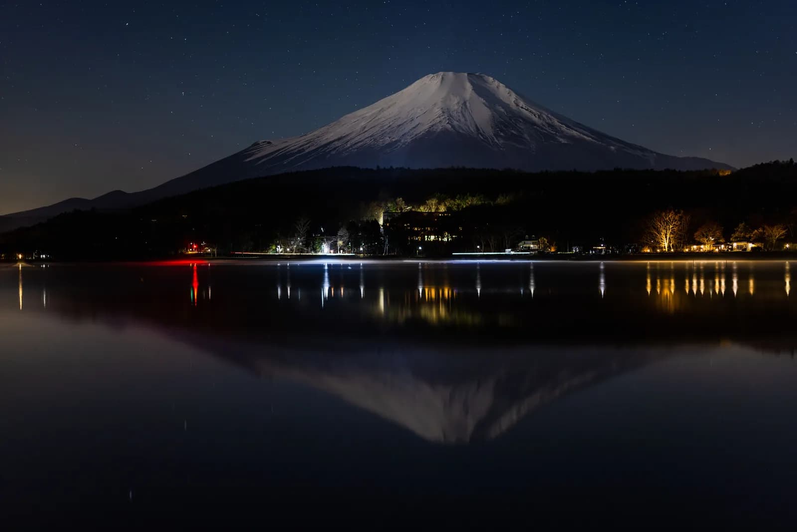 Mount fuji at night with snow capped peak and reflection in lake yamanaka japan