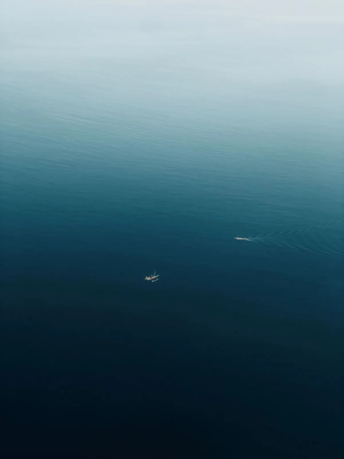 Aerial view of a small fishing boat sailing on the calm deep blue ocean water surface