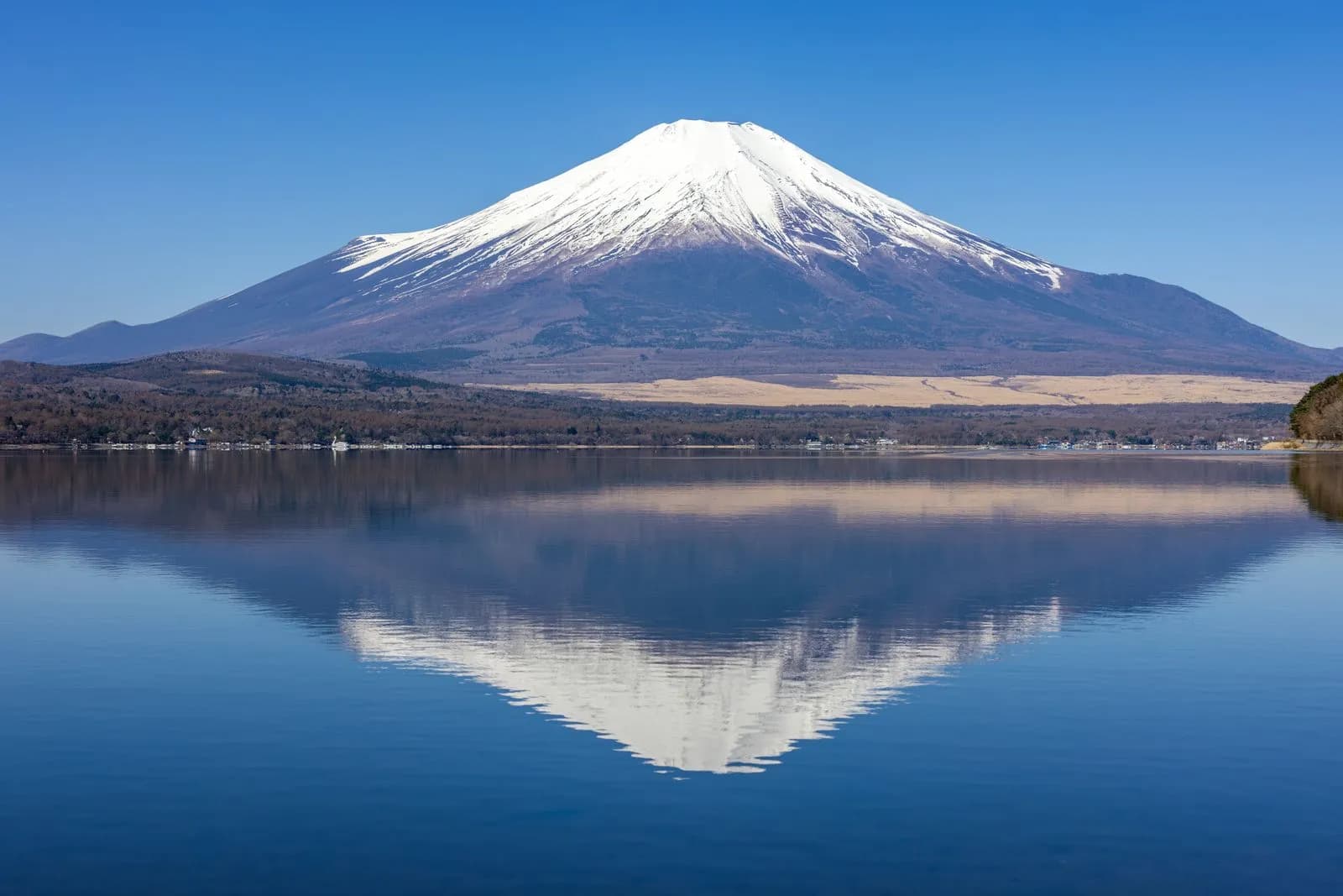 Serene reflection of iconic snow-capped mountain over tranquil lake landscape