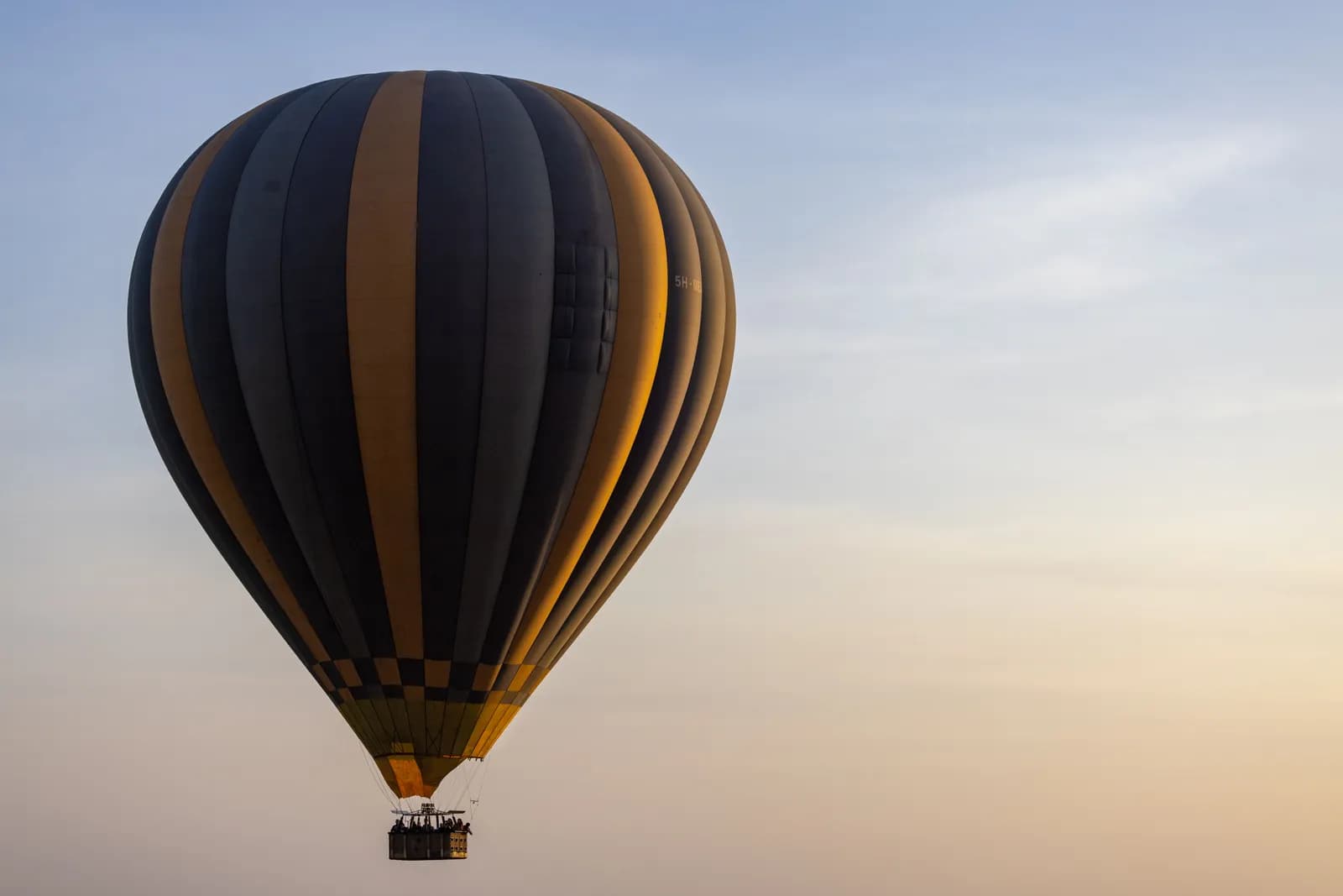 Large hot air balloon flying in the sky during a clear sunrise for travel and adventure concepts