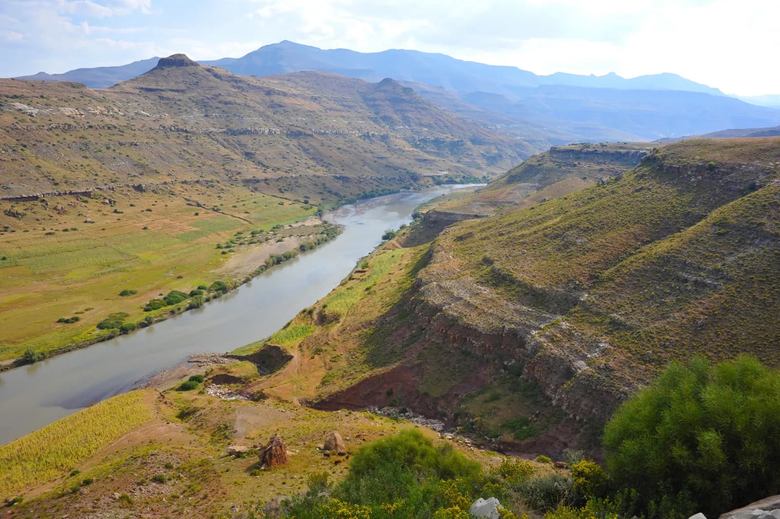 Scenic view of a winding river flowing through a deep valley with rugged mountains in the distance
