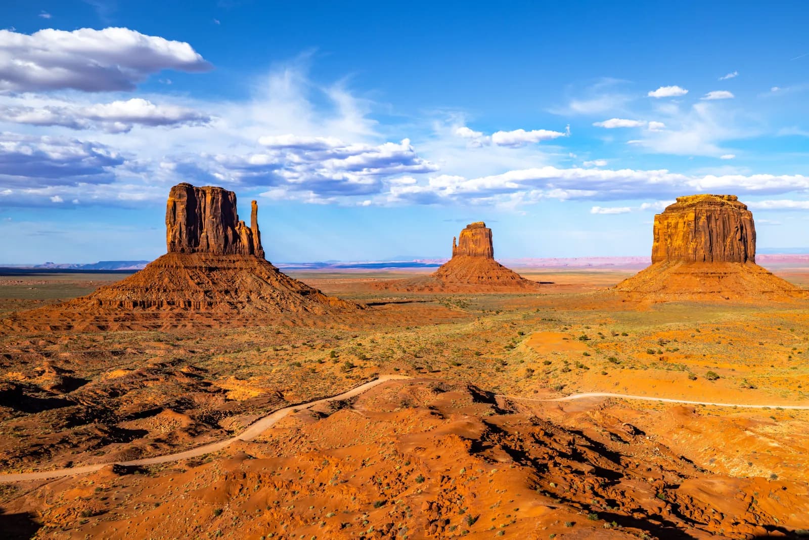Scenic view of monument valley buttes under a bright blue sky with clouds in arizona desert landscape