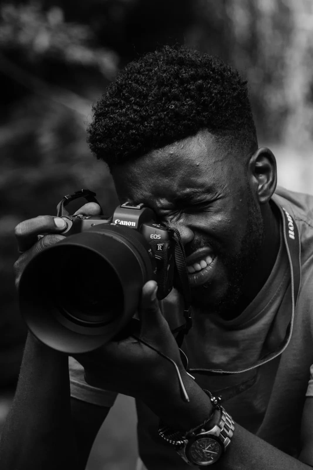Black man photographer holding professional camera taking pictures outdoors in nature