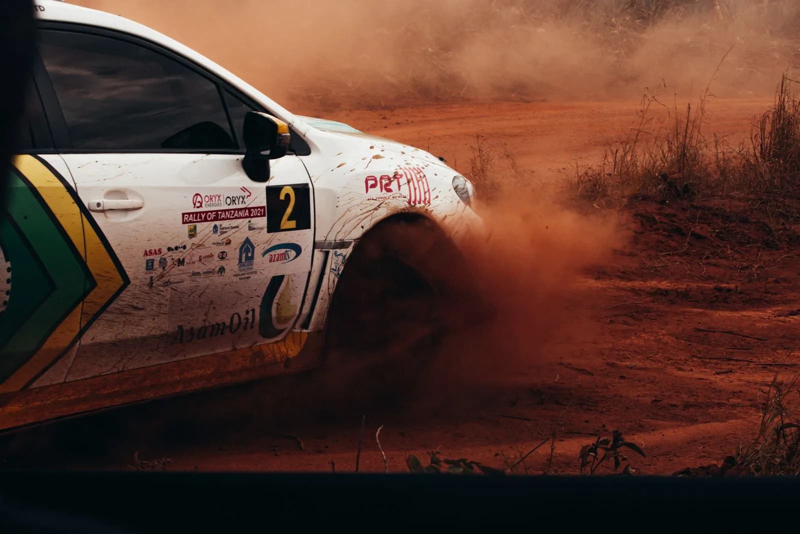 Rally car driving fast on dirt track kicking up dust during a professional off road racing event