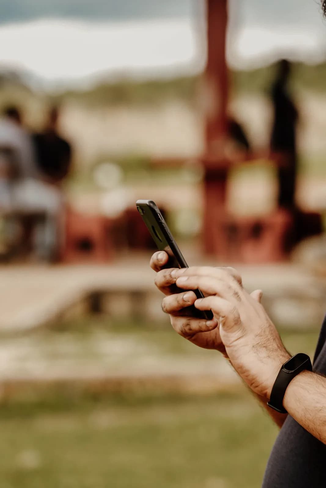 Man holding smartphone outdoors for communication and digital connectivity in a park setting
