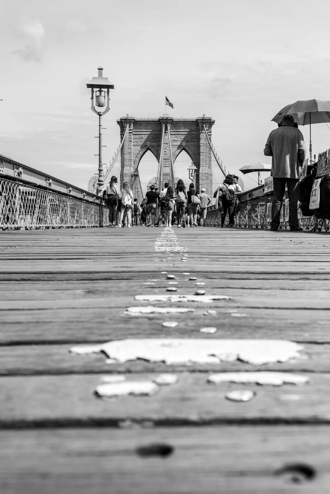 Pedestrians walking on brooklyn bridge wooden walkway in new york city during a cloudy day