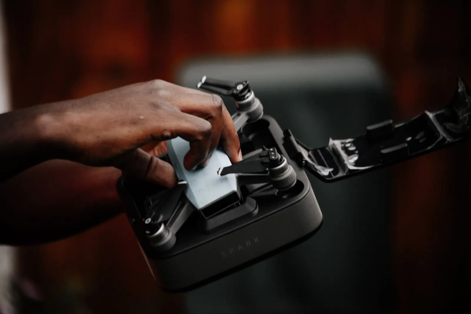 Person placing a small drone into a protective carrying case for travel and storage preparation
