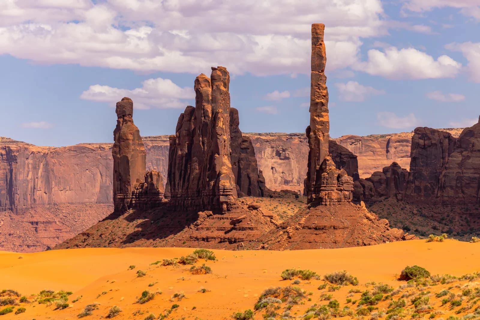 Monument valley totem pole rock formation in the desert landscape under a blue sky with clouds