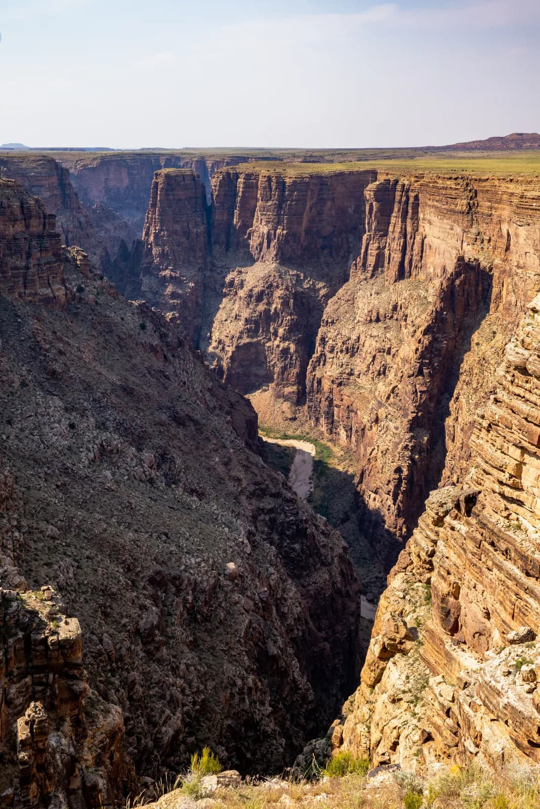 Scenic view of a deep desert canyon with steep rocky cliffs and a winding river at the bottom