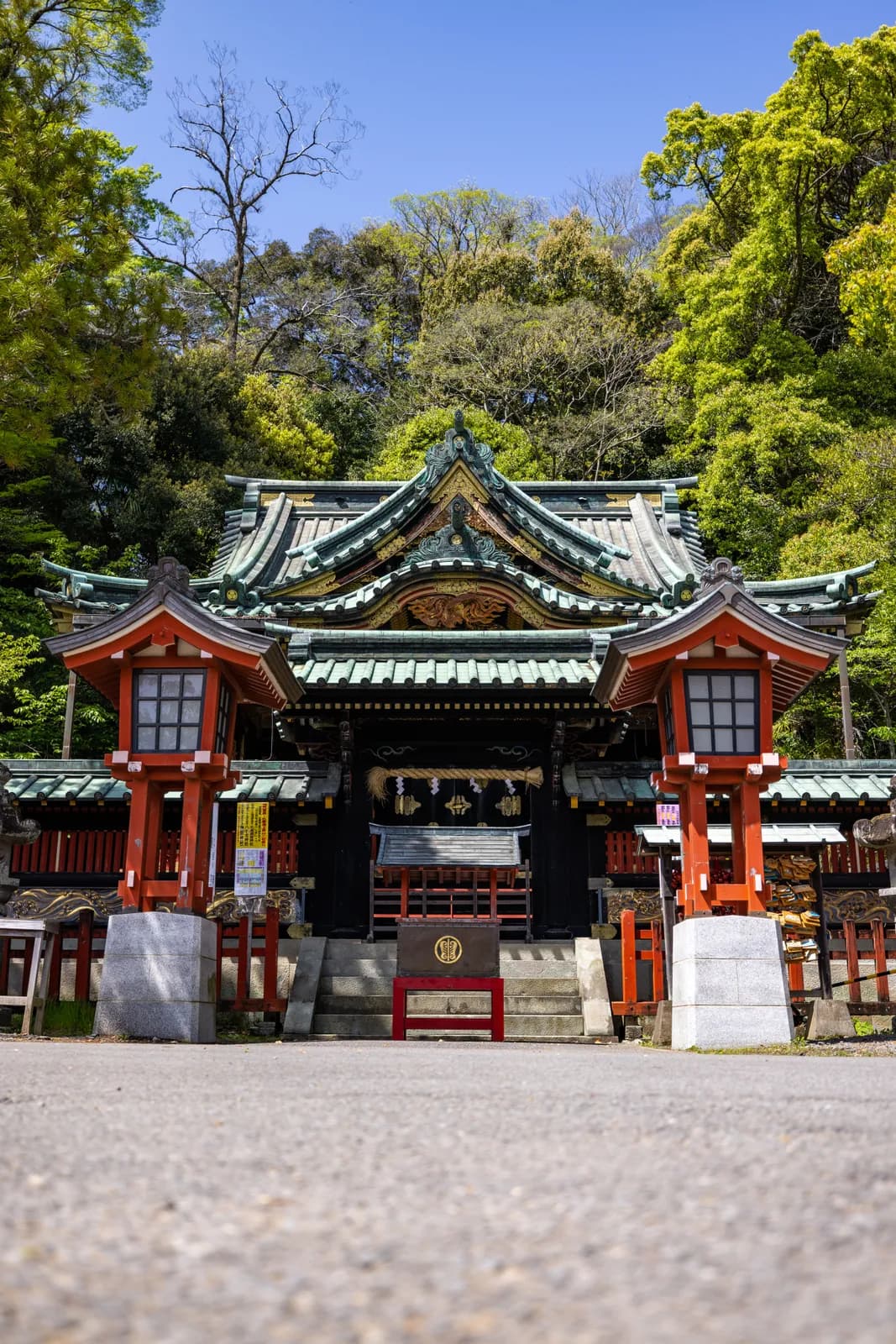 Traditional japanese shinto shrine entrance with red lanterns and lush green forest background