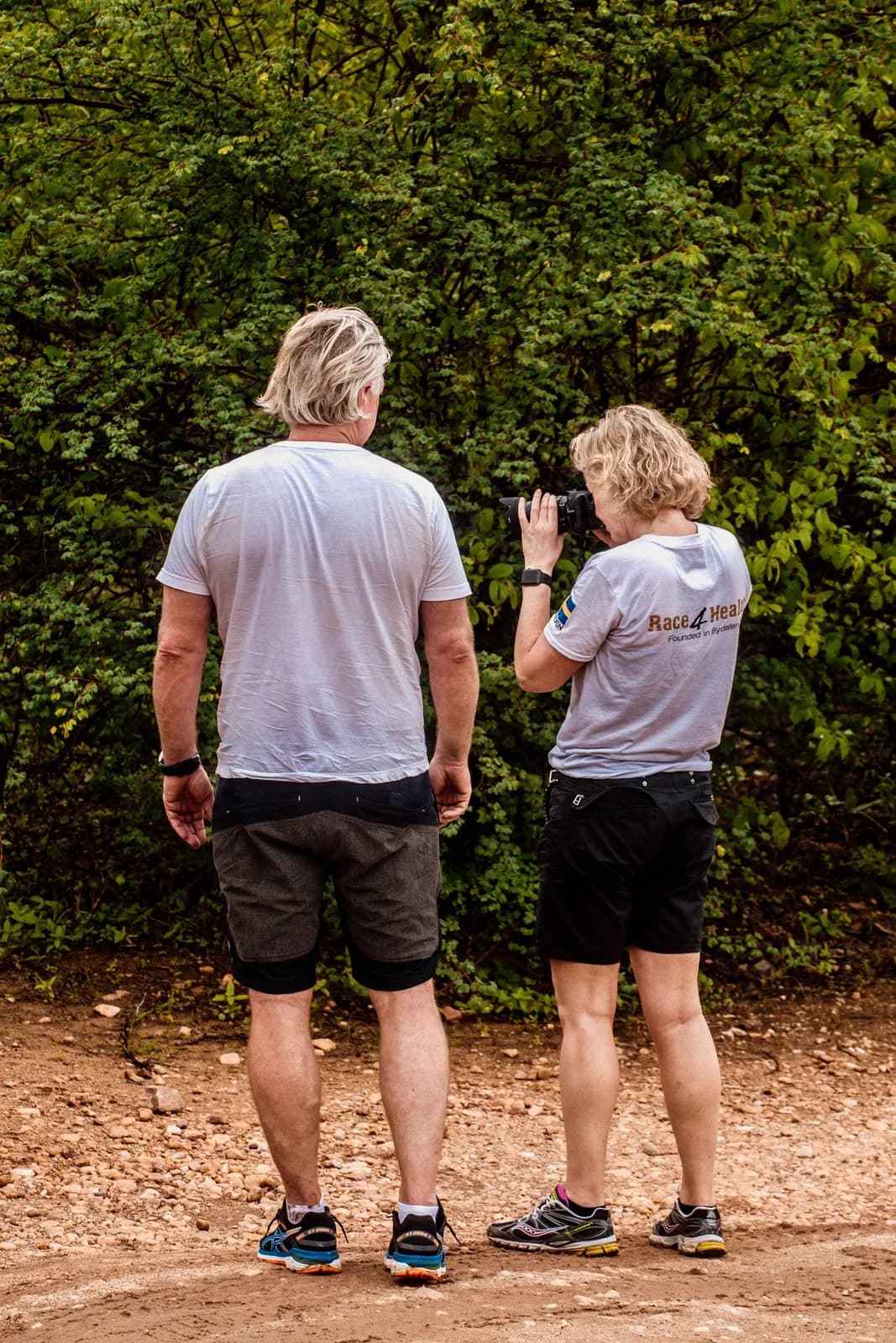 Two hikers using smartphone for navigation on outdoor trail in forest