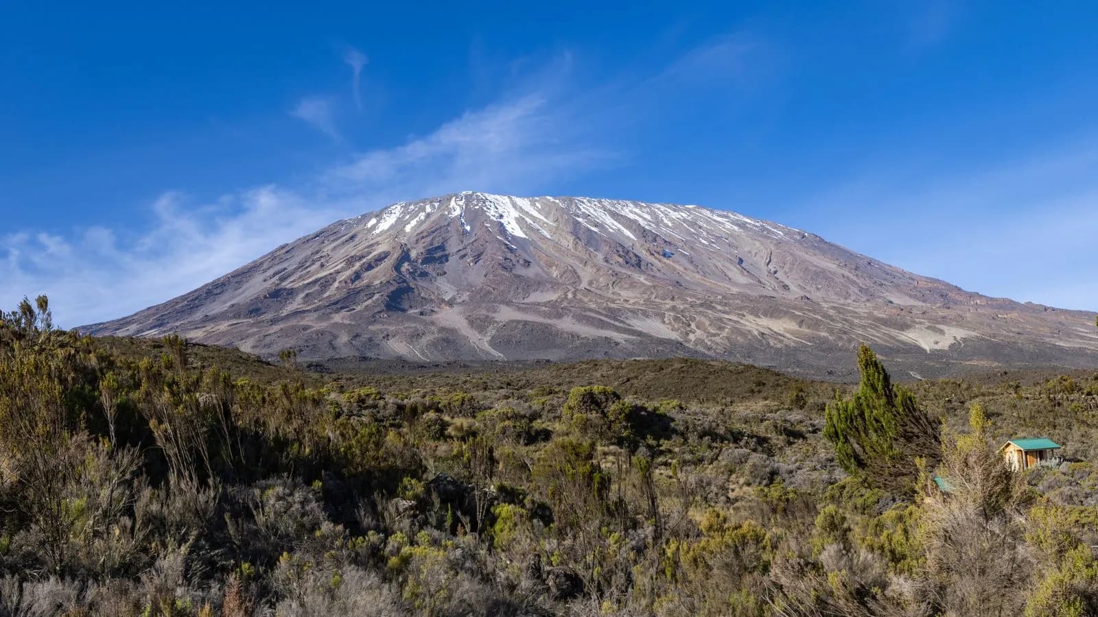 Scenic view of mount kilimanjaro with snow capped peak and small mountain hut in tanzania landscape